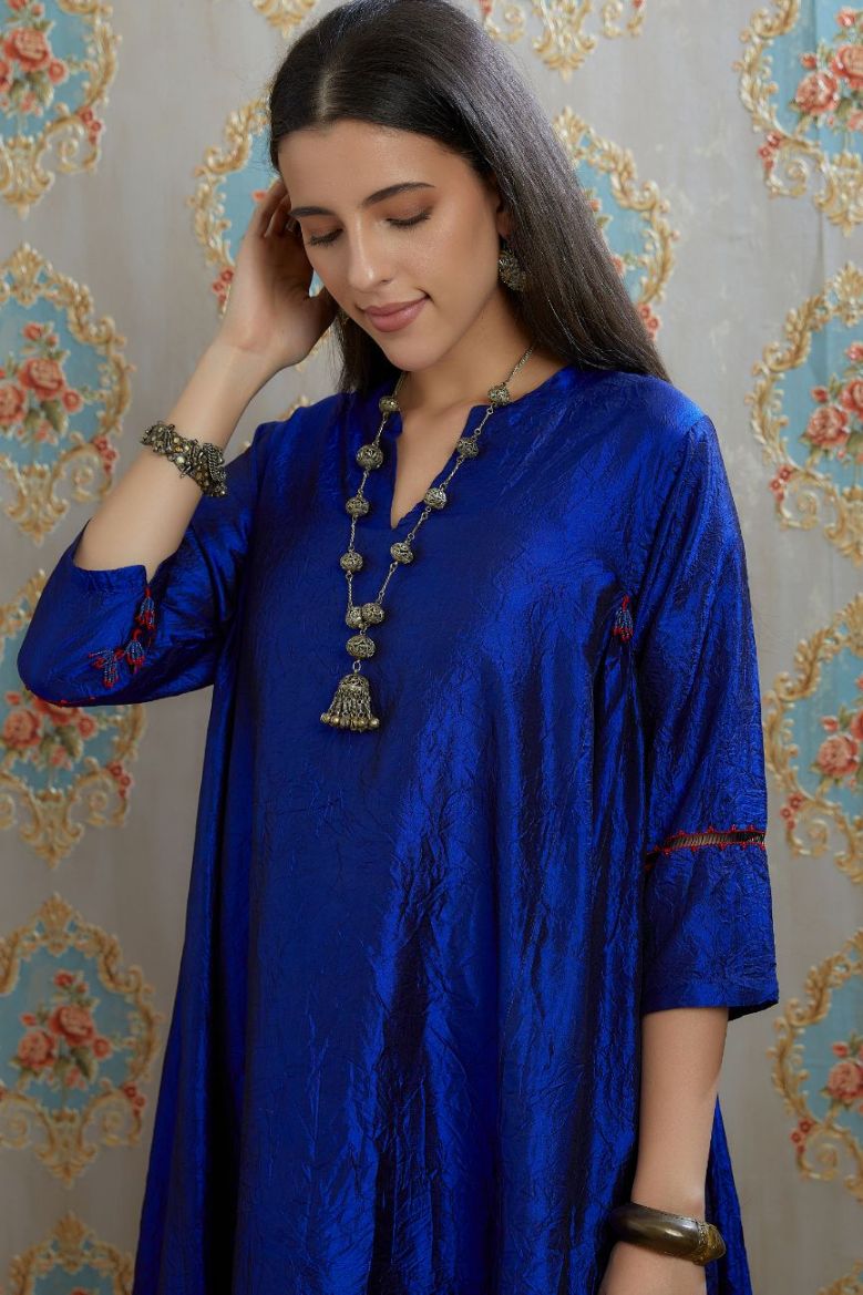 Asymmetric hem blue hand crushed silk kurta with pulled thread embroidery, paired with hand crushed silk pants.