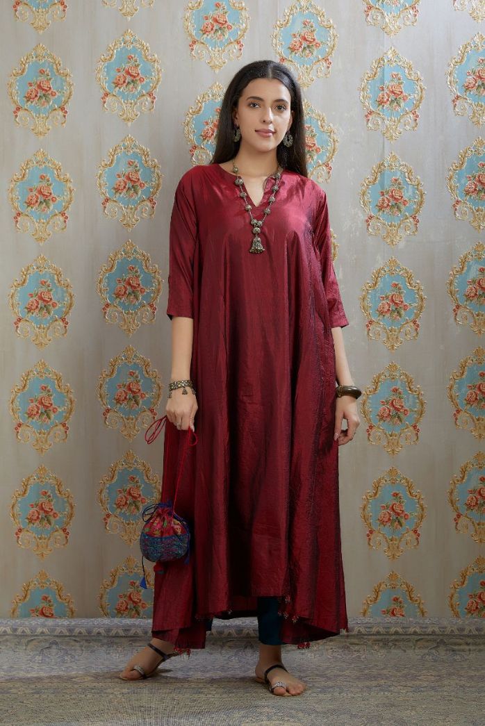 Asymmetric hem maroon hand crushed silk kurta highlighted with beaded tassels, paired with hand crushed straight silk pants.