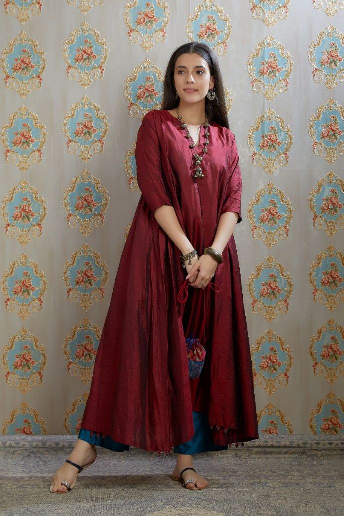 Asymmetric hem maroon hand crushed silk kurta highlighted with beaded tassels, paired with hand crushed straight silk pants.