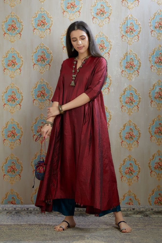 Asymmetric hem maroon hand crushed silk kurta highlighted with beaded tassels, paired with hand crushed straight silk pants.