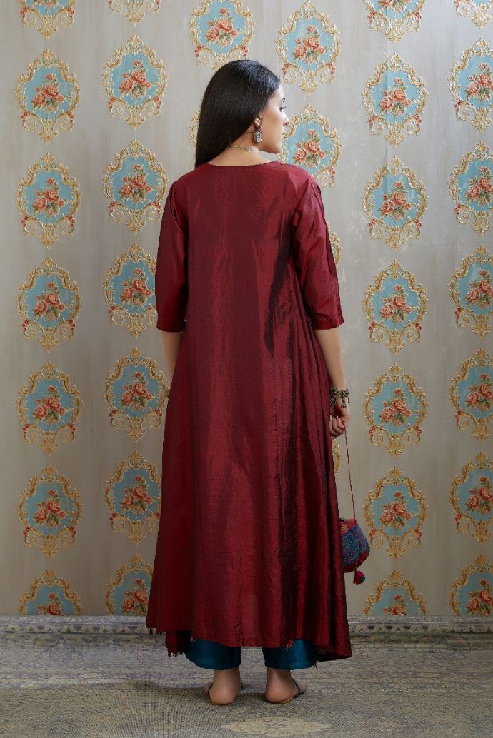 Asymmetric hem maroon hand crushed silk kurta highlighted with beaded tassels, paired with hand crushed straight silk pants.